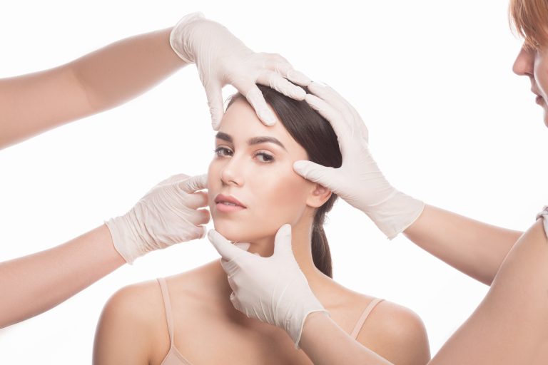 A young woman undergoing a facial skin examination by multiple professionals wearing medical gloves, assessing her skin for aesthetic treatments, dermatology consultation, or cosmetic procedures.